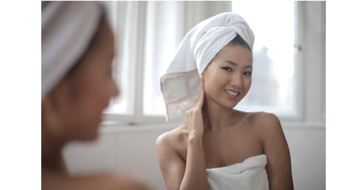 woman in a towel looking at her skin